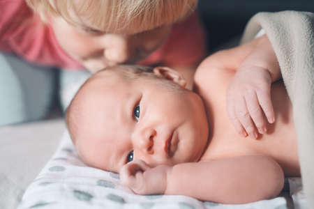 Siblings bonding. Sister kissing her little brother. Child toddler girl and newborn baby boy....