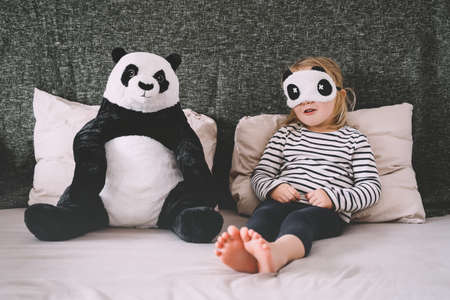 Cute little girl with soft big plush panda at home. Concept of family, healthy sleep of child, upbringing, parenting. Ð¡hildhood and friendship.の写真素材