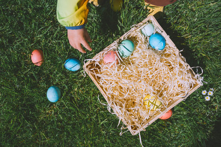 Colorful Easter eggs in basket. Children gathering painted decoration eggs in spring park. Kids hunt...