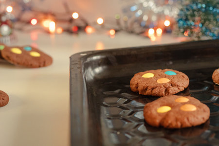 Homemade cookies on a baking sheet. Beautiful New Year's background. Baking with colored candies. In the background the garland is burning.の写真素材