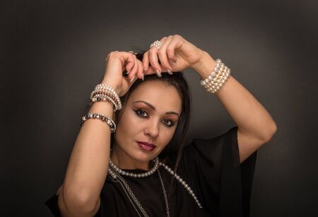 Beauty woman with pearls on the dark background