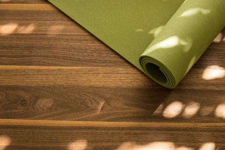 Yoga mat on a wooden background. Equipment for yoga. Concept healthy lifestyle. Lots of copyspaceの写真素材