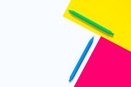 Colored pens isolated on white background with pink and yellow elements. Abstract design. Minimalist geometric style. Flat lay. With copy space. Concept of work and education.の写真素材