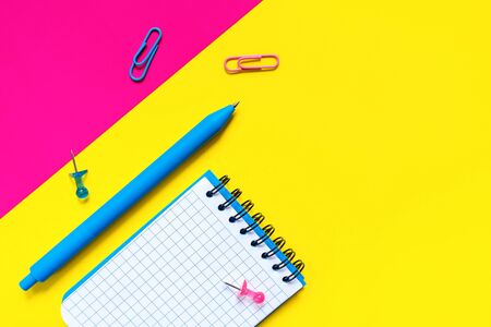 School and office supplies on color background. Blue pen and open notepad with blank sheet. Concept of back to school and education. Minimalist design. Geometric style. Flat lay. With copy space.の写真素材