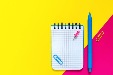 School and office supplies on color background. Blue pen and open notepad with blank sheet. Concept of back to school and education. Minimalist design. Geometric style. Flat lay. With copy space.の写真素材