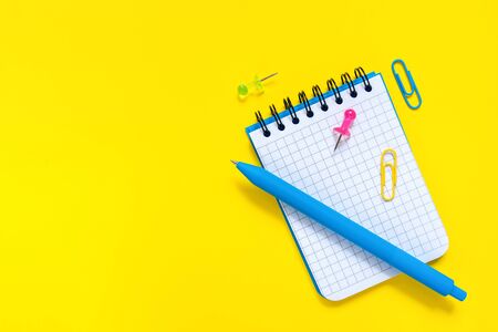 School and office supplies on yellow background. Blue pen and open notepad with blank sheet. Concept of back to school and education. Minimalist flat lay. Empty place for writing. With copy space.の写真素材