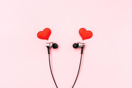 Red hearts with black music earphones for smartphone on pink pastel background. Romantic and love concept. Beautiful gift postcard. Minimalist flat lay. Empty place for writing. Copy space. Top view.の写真素材
