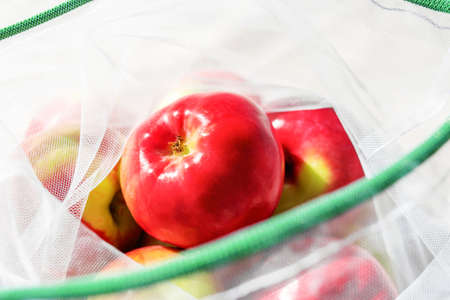 Fresh ripe apples in reusable eco-friendly mesh bag. Sunny day. Plastic free, zero waste and sustainable lifestyle concept. Reusable using. Environmental concern. Closeup view.の写真素材