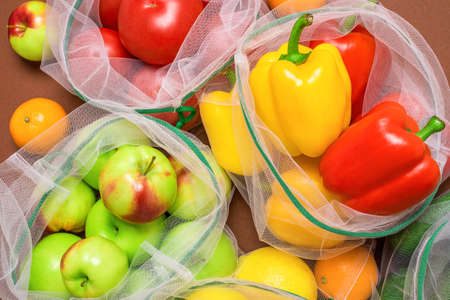 Fresh and juicy fruits and vegetables in reusable eco-friendly mesh bags. Plastic free, zero waste, and sustainable living concept. Reusable using. Top view. Closeup view.の写真素材