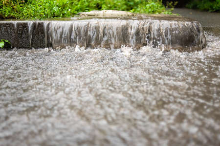 The stream of water flows down to the pedestrian area. Rainy autumn weather. Heavy flood. Street...