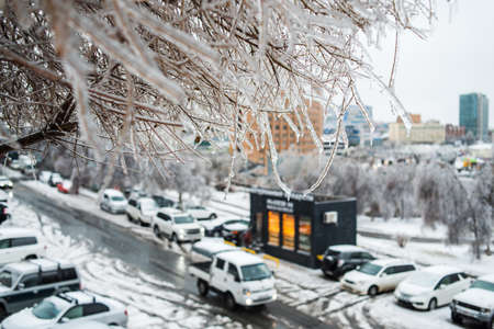 View of the city and roads in bad snowy weather. Trees covered with ice and bent to the ground. City in the winter. Ice storm weather.の写真素材