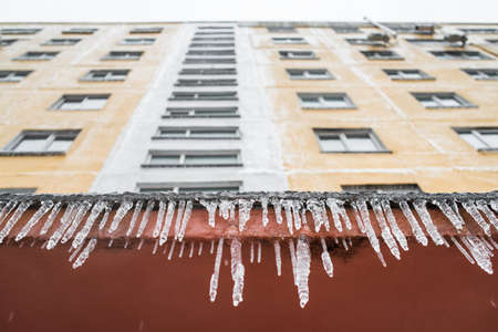 Beautiful Icicles hang from the visor of the house entrance. Ice storm, bad snowy weather. Winter time.の写真素材
