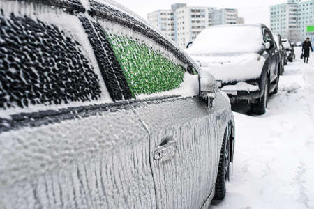 Car covered with ice and icicles after freezing rain. Ice covered car window close up. Ice storm cyclone in November Vladivostok, Russia. Snowy weather. City in winter. Winter frosty scenes.の写真素材