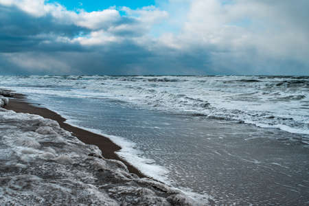 Winter landscape with frozen sea and icy beach. Storm and snow weather. Dramatic seascape.の写真素材