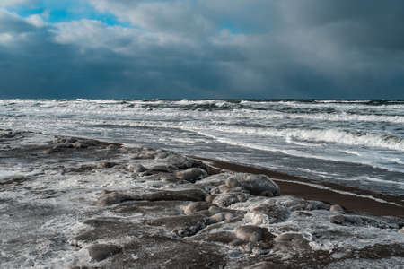 Winter landscape with frozen sea and icy beach. Storm and snow weather. Dramatic seascape.の写真素材