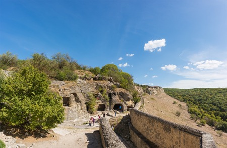 BAKHCHISARAY, REPUBLIC of CRIMEA, RUSSIA - SEPTEMBER 13.2016: Tourists are considering monastic cells in the rock. Over the southern gate of the medieval town-fortress Chufut-Kaleのeditorial素材