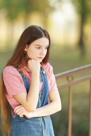 Brooding long-haired beautiful teenage girl is thinking about something sad. Sadnessの写真素材