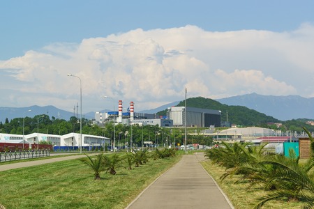 Russia, Sochi, Krasnodar region - June 06.2017: Palm Avenue and Adler thermal power plant in the background of the cloudy sky area in the Imeretinskaya lowland of Adler district of the resort townのeditorial素材