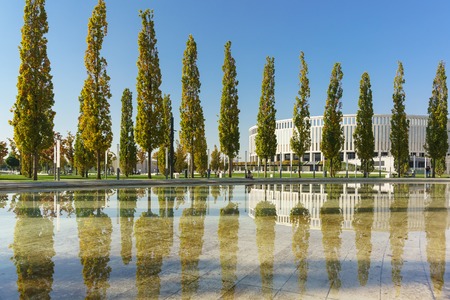 Krasnodar, Russia-October 19, 2018: Pyramidal poplars against the background of a modern football stadium are reflected in the semicircular reservoir of the new city Park Krasnodar. Sunny autumn dayのeditorial素材