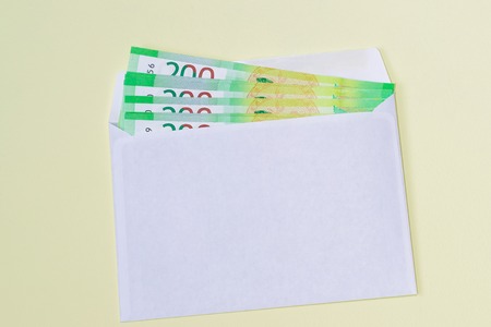 White envelope with money on yellow background. Money order