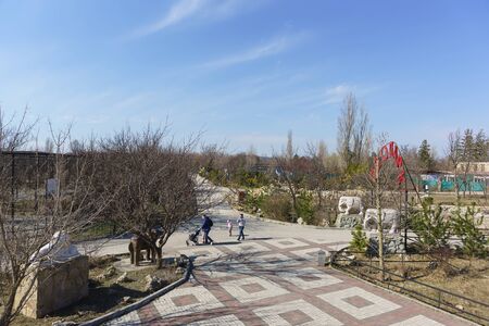 Belogorsk, Crimea, Russia-March 10, 2019: People with children walk on the territory of the Lviv Taigan Safari Park. A cloudy day in early spring. Russian text "the Zoo"のeditorial素材