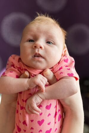 A small newborn girl in the arms of her mother. After feeding, it is recommended to hold the baby...