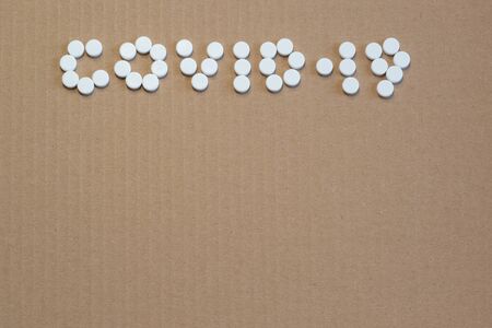 The word COVID-19 from the tablets on the grey cardboard. The global problem of the spread of a serious disease. Copy spaceの写真素材