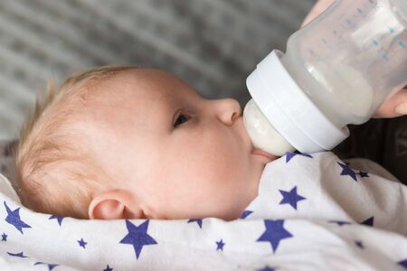 Feeding a small newborn girl with formula from a bottle. Artificial feeding