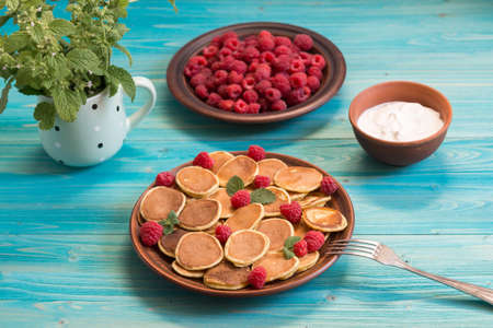 Pancake cereals and red ripe fresh raspberries in a brown plate on a blue wooden table. Delicious...