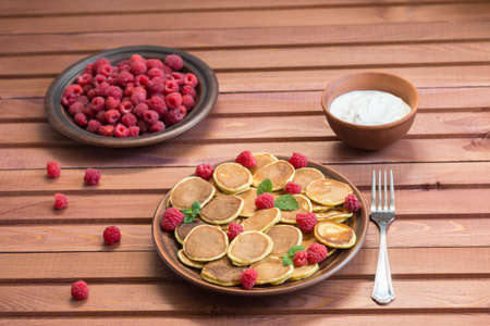 Pancake cereals and red ripe fresh raspberries in a brown plate on a wooden table. Delicious summer...