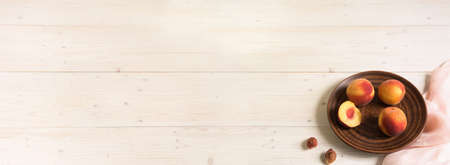 A large banner with peaches on a whitewashed wooden background. The peaches are on a brown clay plate. Copy spaceの写真素材
