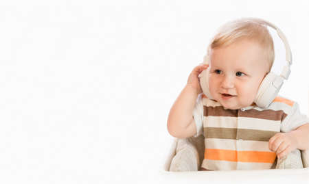 A small happy child listens to a musical fairy tale with headphones. Copy space. White backgroundの写真素材