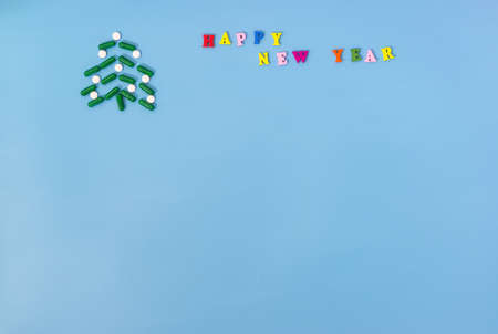 A Christmas tree made of green capsules and white pills and the inscription Happy new year on a blue...