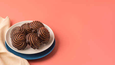 Traditional Russian vanilla marshmallows in chocolate glaze in white and blue plates on a pink background. Colorful table and linen textiles. Copy spaceの写真素材