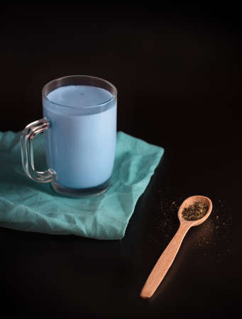 Moon milk is a drink made from milk and blue water. Thai flower tea in a glass Cup on a black backgroundの写真素材