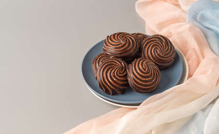 Traditional Russian vanilla marshmallows in chocolate glaze in blue and white plates on a gray...