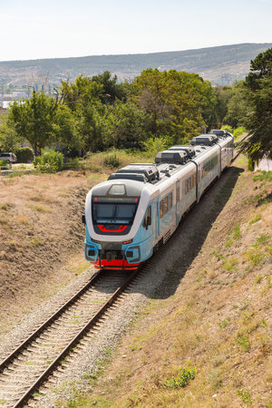 Russia, Crimea, Feodosia September 18, 2020-an electric locomotive with passenger cars goes Through the city to the railway station. The car lights up the inscription in Russian Feodosiaのeditorial素材