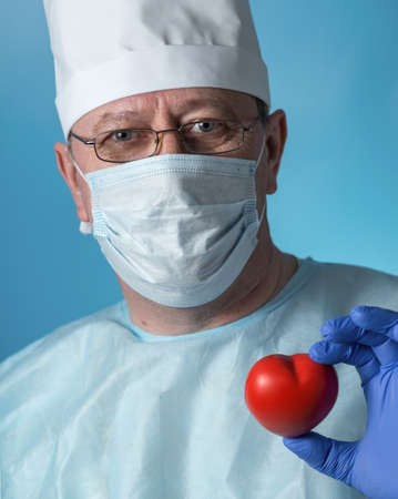 Portrait of a middle-aged serious experienced cardiologist surgeon in medical clothing: cap, gloves,...