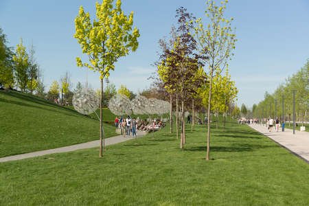 Krasnodar, Russia-may 02, 2021: People relax and walk along the paths in the Krasnodar Park. The fresh spring greenery of nature and the whimsical architecture of the original lampsのeditorial素材