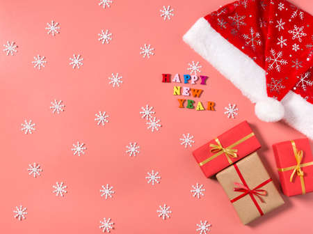 Boxes with gifts, white snowflakes, Santa Claus hat and the inscription happy new year on a red...
