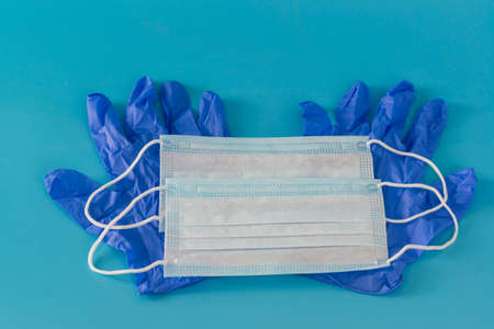 Two new medical masks and a pair of blue nitrile gloves are on the table. Personal protective...