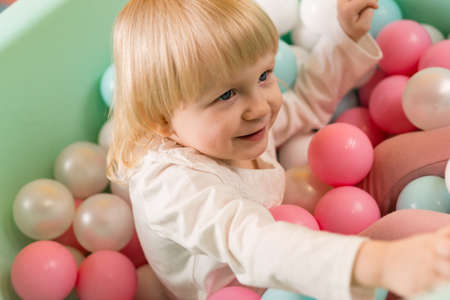 A little cheerful girl is playing in a dry pool with colorful balls. smile. close-upの写真素材