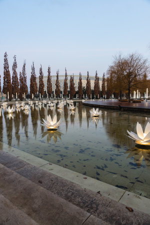 Russia, Krasnodar - January 04, 2023: Descent into an artificial pond with flower-shaped lanterns and pyramidal oaks around the perimeter in Galitsky Parkのeditorial素材