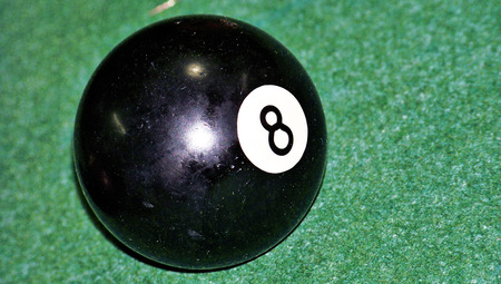 Black eight ball of billiard game on green background