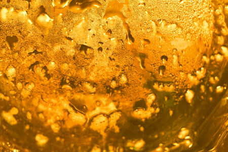 Golden yellow drink drops on glass abstract background closeupの写真素材