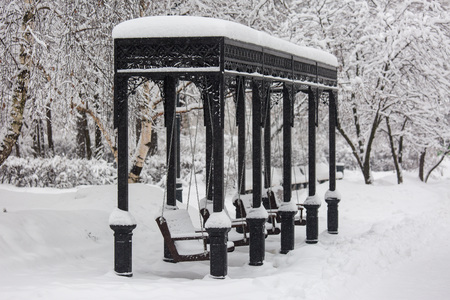 Park swing during snowstorm at winter in Moscow, Russia. Scenic view of a snowy city street. Moscow snowfall background. Cold silent town alley.の写真素材