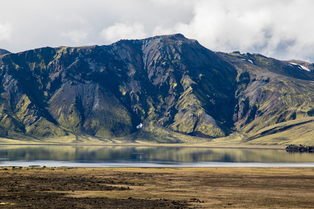 Dramatic iceland landscape with a green hill and black lava and and blue mirror mountain lake. Icelandの写真素材