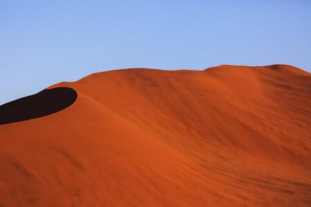 Beautiful landscape with red huge sand dunes at sunset in desert. Sossusvlei, Namib Naukluft...