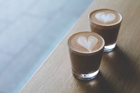 Two glasse cups of capuccino on the wooden table.の写真素材
