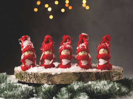 A table Christmas decoration with five red figurines of girls in Christmas suits on a wooden plate.の写真素材
